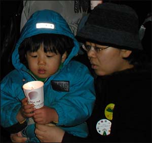 엄마의 무릎위에서 촛불을 밝히고 있는 아이 